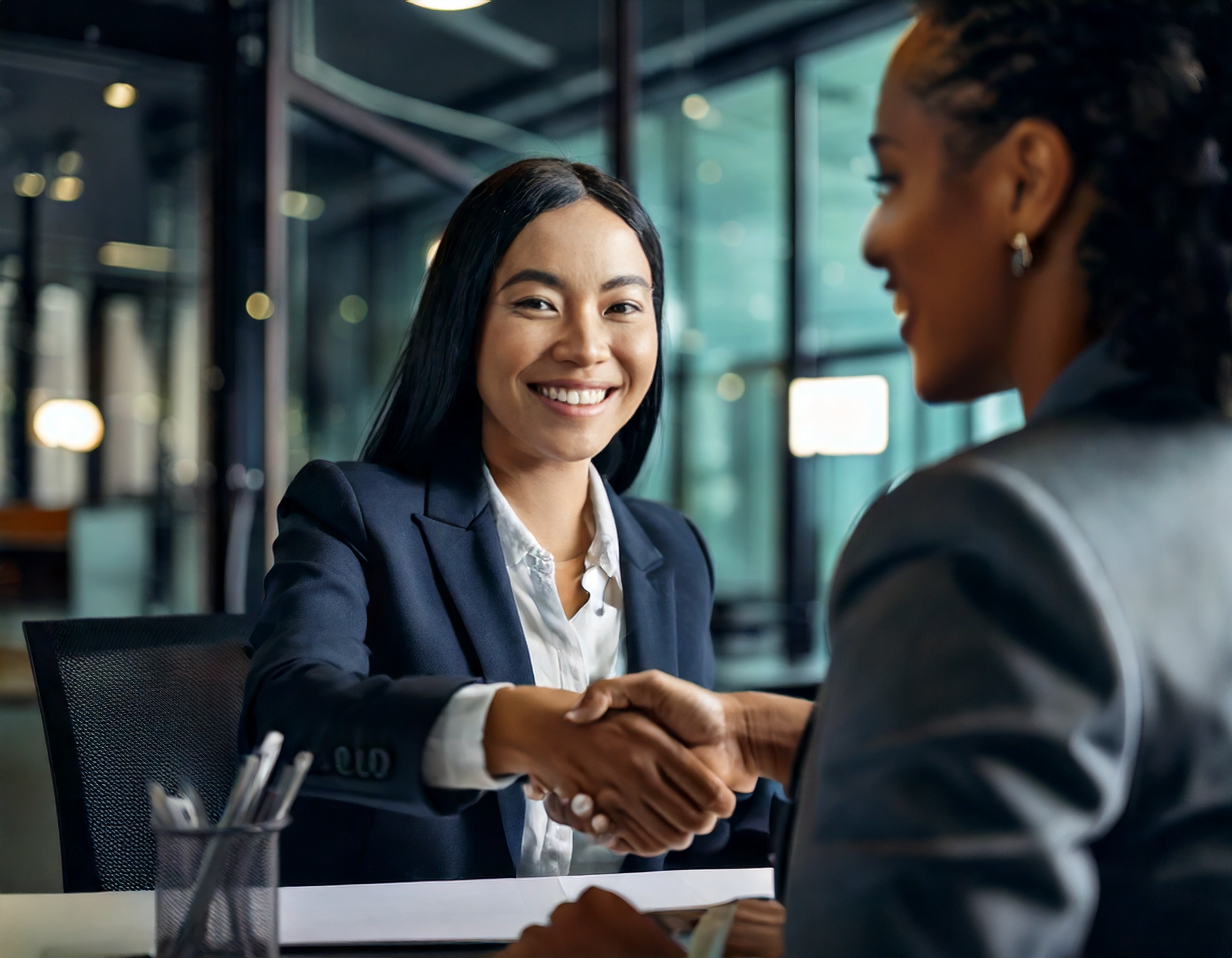 Two women shaking hands in a successful sales interview, representing trust and connection in the real estate industry.